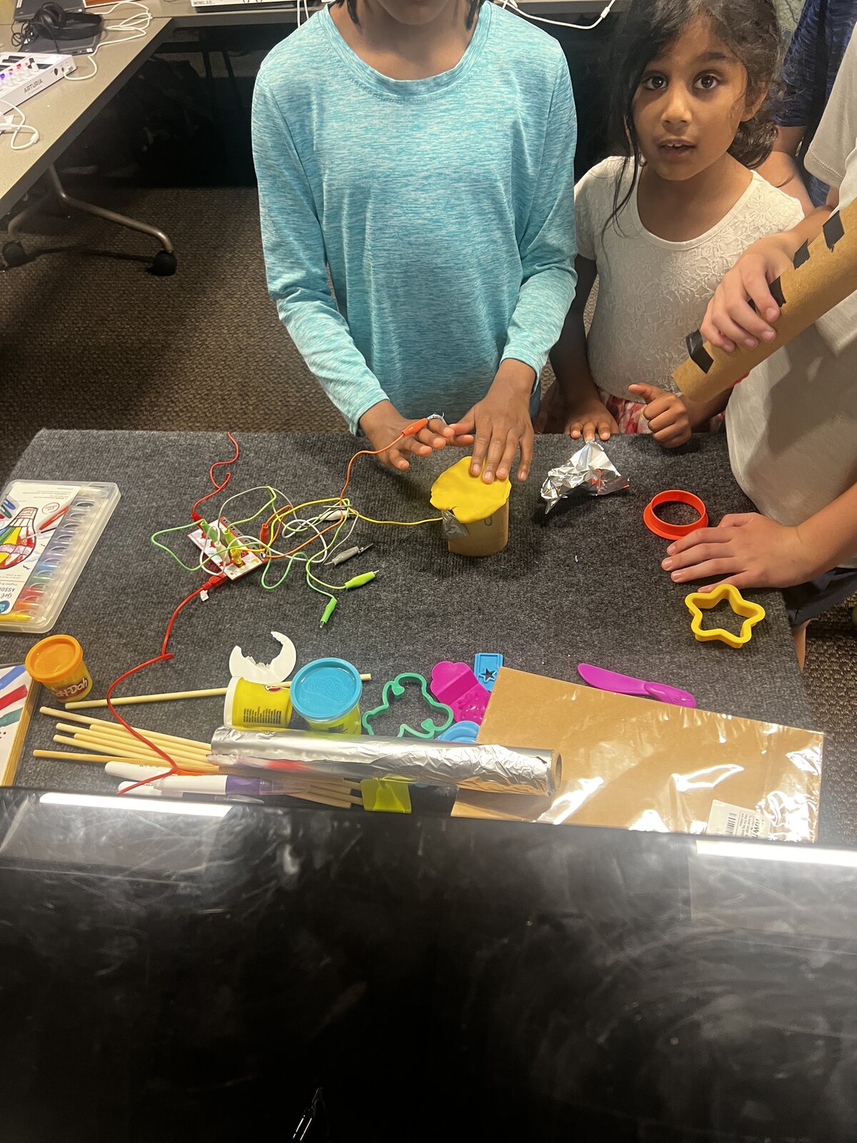A young student building an electronic instrument with foil and Play-Doh