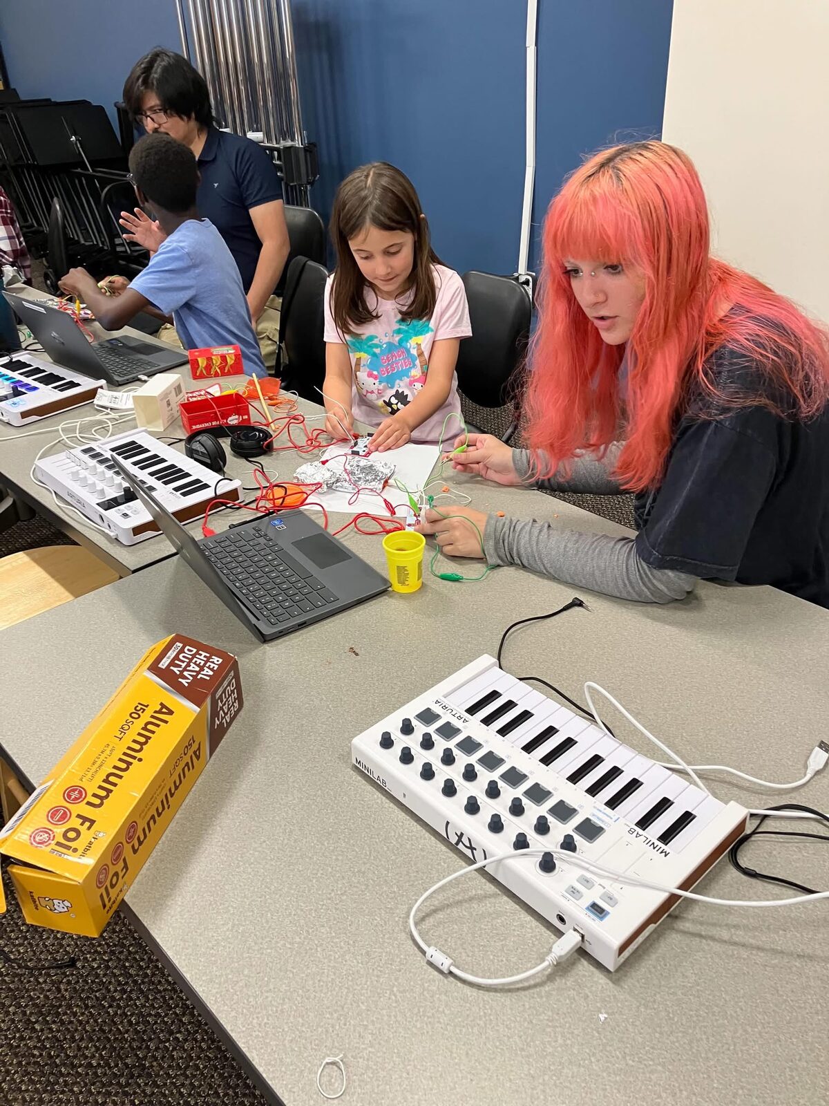 A mentor helping a student build an electronic instrument