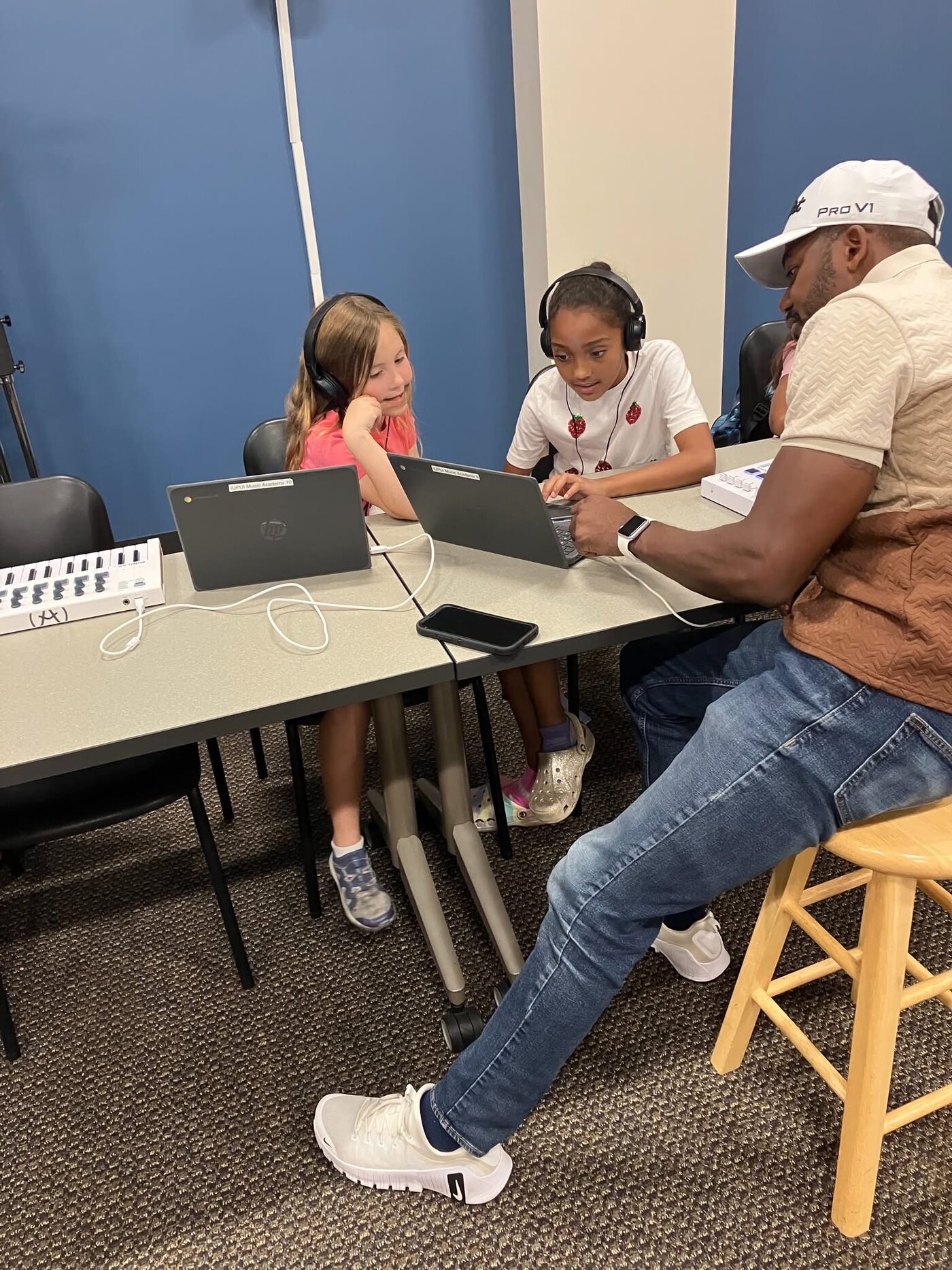 An instructor working with two students at a MIDI keyboard