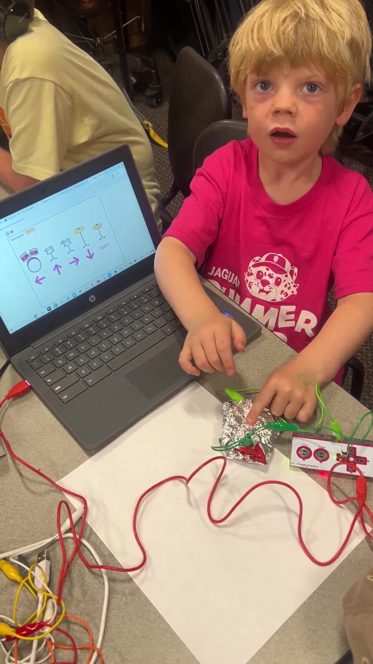 A student plays a MakeyMakey drum kit they built